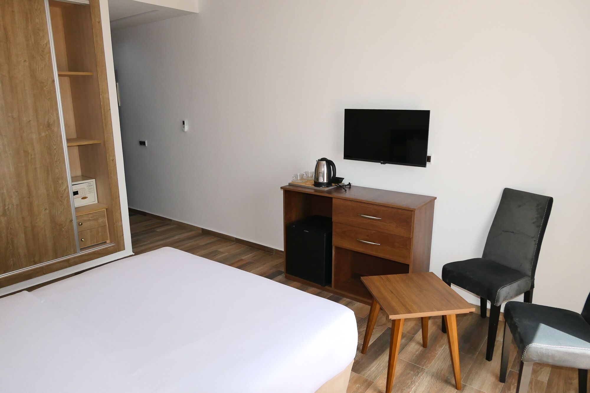 Et hotelværelse med en seng, et skrivebord med stol, et fjernsyn og et lille bord.
