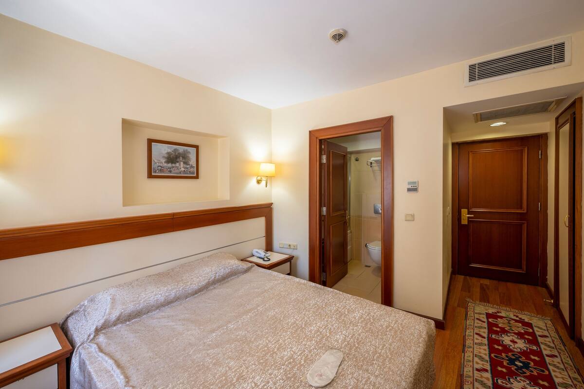 Une chambre d’hôtel avec un lit, une table de chevet, une lampe et un tableau encadré au mur.