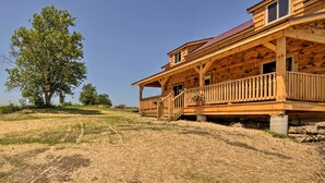 Eine Holzhütte mit Veranda und einem großen Baum in der Nähe.