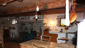 Eine rustikale Küche mit Holzbalken, Steinwänden und einem Holztisch mit Stühlen.