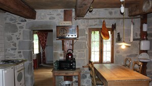 Eine rustikale Küche mit Steinwand, Holztisch und einem alten Radio.