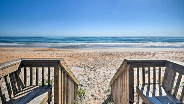 A wooden deck leading to a beach with a clear view of the ocean. - Coastal Condo Escape: Steps to Beach (Ormond Beach)