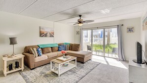 A living room with a sofa, coffee table, and a television. - Coastal Condo Escape: Steps to Beach (Ormond Beach)