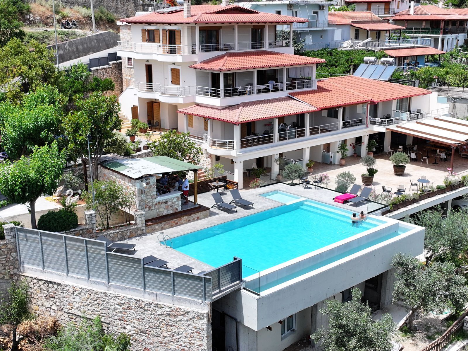 A multi-story hotel with a rooftop pool, outdoor seating, and a stone facade.