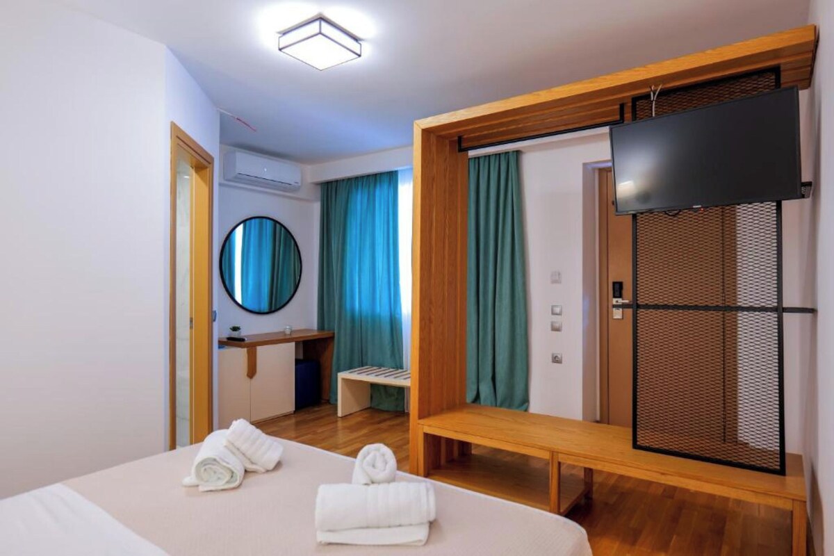 A hotel room with a bed, a bench, a TV, and a mirror.