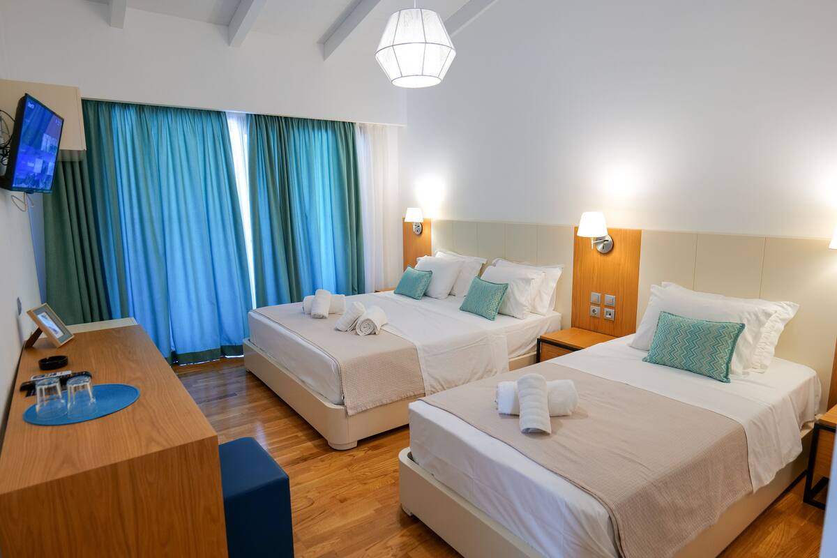 A hotel room with two beds, a desk, and a TV.