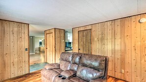 Una habitación con paneles de madera, un sofá de cuero y suelo de madera.