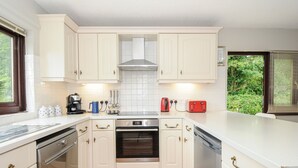Uma cozinha moderna com armários brancos, forno de aço inoxidável e lava-louças.