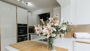 A modern kitchen with white cabinetry, a wooden countertop, and a vase with flowers. - Luxe 3 Bed property with beautiful garden room. (Harrogate)