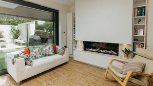 A modern living room with a white sofa, a wooden floor, a fireplace, and a bookshelf. - Luxe 3 Bed property with beautiful garden room. (Harrogate)