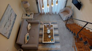 A modern living room with a sofa, coffee table, and a staircase. - Luxury New Loft Apartments in Halkidiki (Agios Mamas, Chalkidiki)