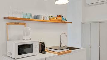 A compact kitchen with a microwave, coffee maker, and a sink.