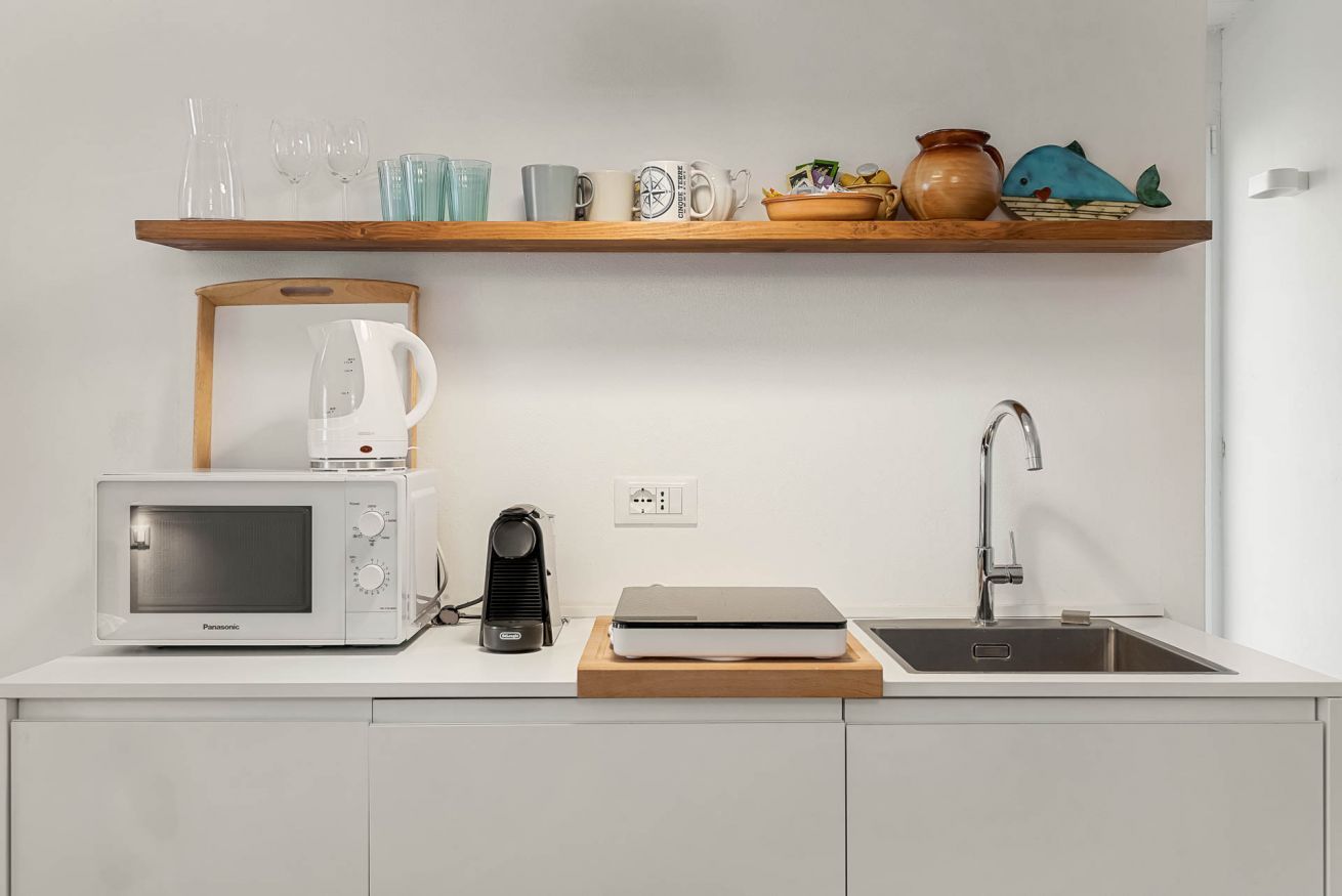 Una cucina con forno a microonde, bollitore, macchina del caffè e lavello.