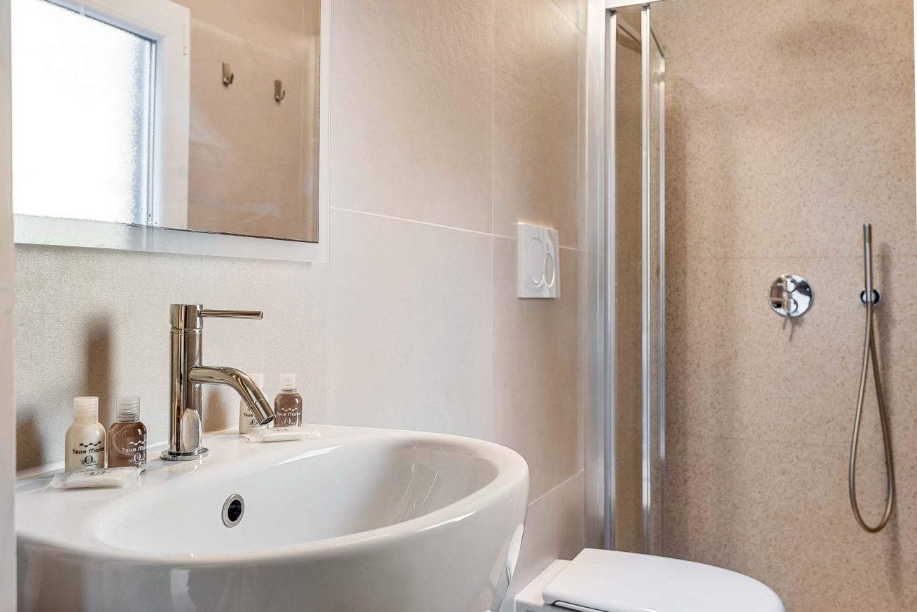 A bathroom with a large sink, a mirror, a shower, and a toilet.