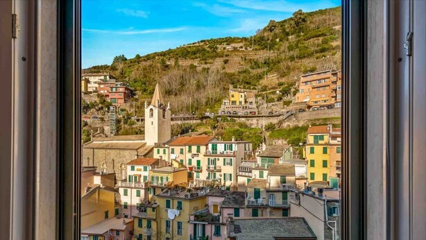 A view of a coastal town with buildings, a church, and a hill in the background. - GuestHost - Riomaggiore cozy studio x4! (Riomaggiore)
