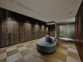 A modern lobby with a checkered floor, a seating area, and a row of lockers.