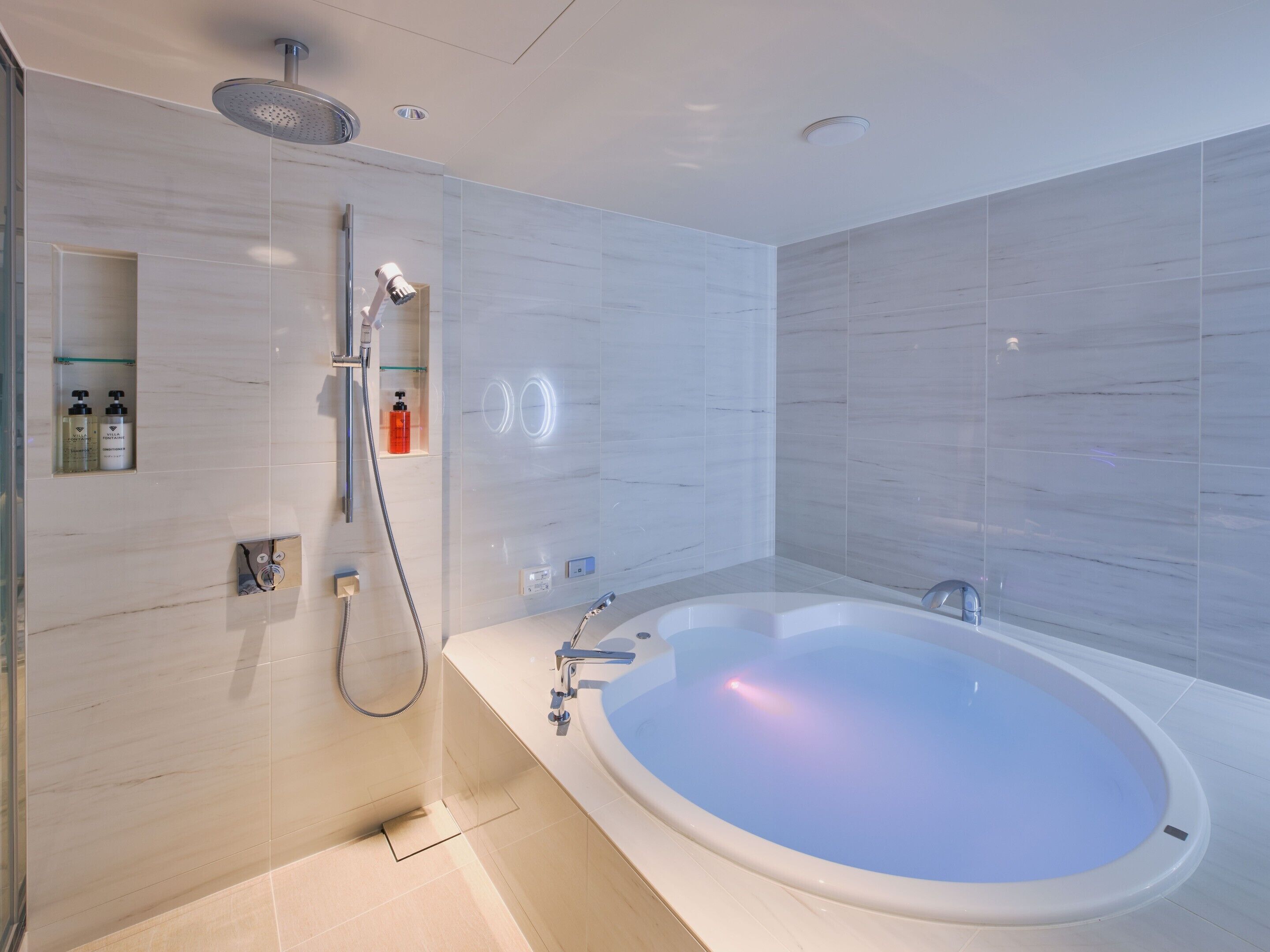 Une salle de bain moderne avec une grande baignoire, une pomme de douche et une cabine de douche en verre.