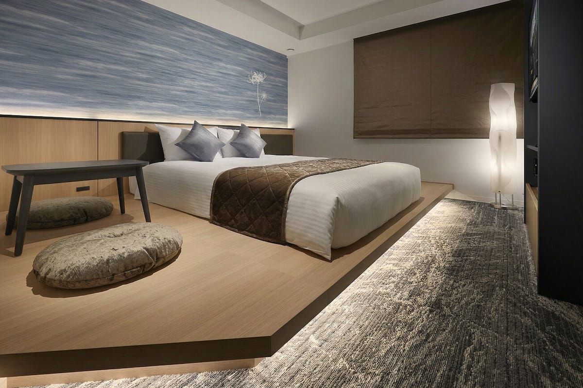 Une chambre à coucher moderne avec un lit, une table de chevet et un grand tableau abstrait accroché au mur.
