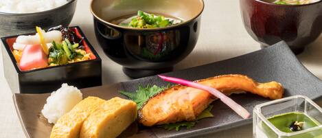 A variety of Japanese dishes including rice, salmon, and a green sauce.