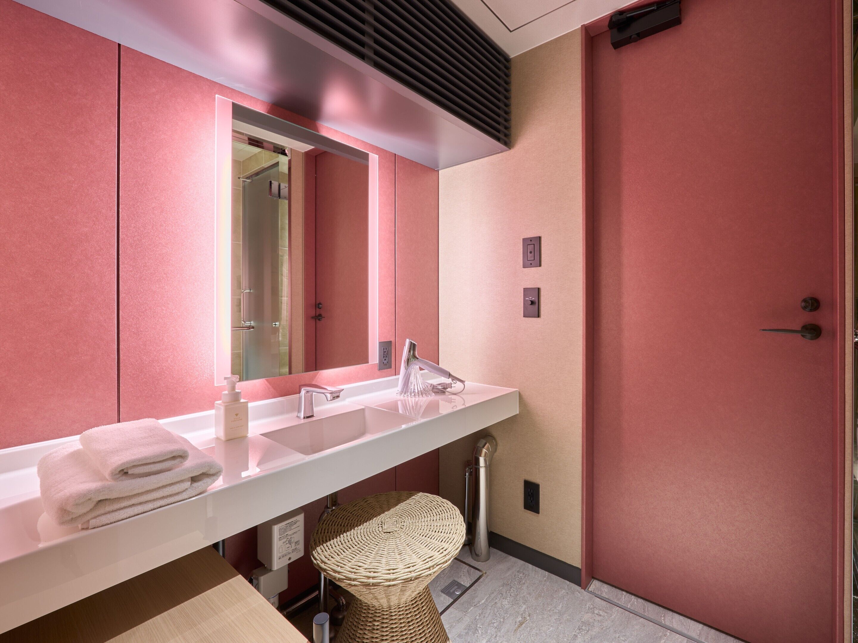 Een moderne badkamer met een wit wastafelmeubel, een grote spiegel en een rode deur.