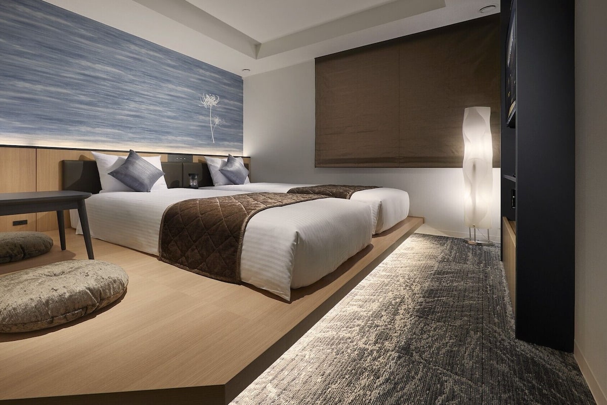Une chambre d’hôtel moderne avec un grand lit, un bureau, une chaise et une grande fenêtre.