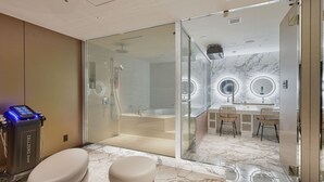Een moderne badkamer met een douchecabine van glas, een wastafel met twee spiegels en een massagestoel.