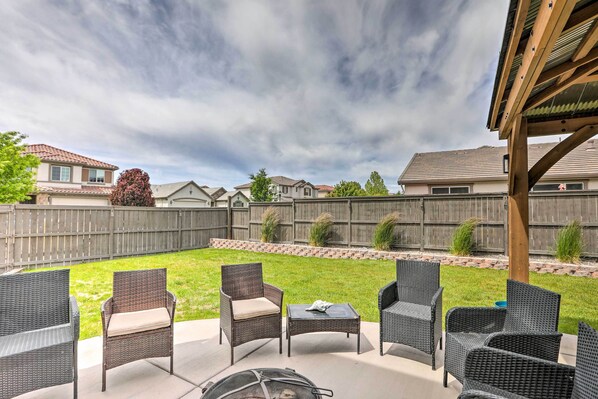 An outdoor patio with wicker furniture and a fire pit.