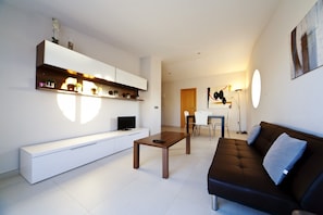 Uma sala de estar moderna com um rack branco, um sofá marrom, uma mesa de centro e uma área de jantar com mesa e cadeiras.