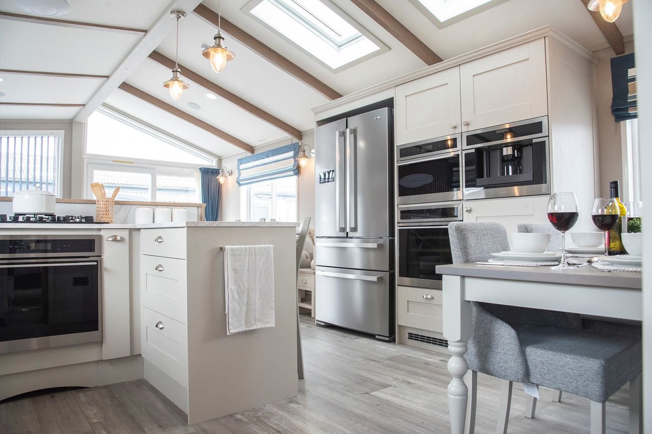 A modern kitchen with a built-in oven, a large refrigerator, and a dining area with a table set for two.