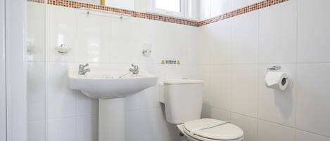 A bathroom with a white sink, toilet, and a window.