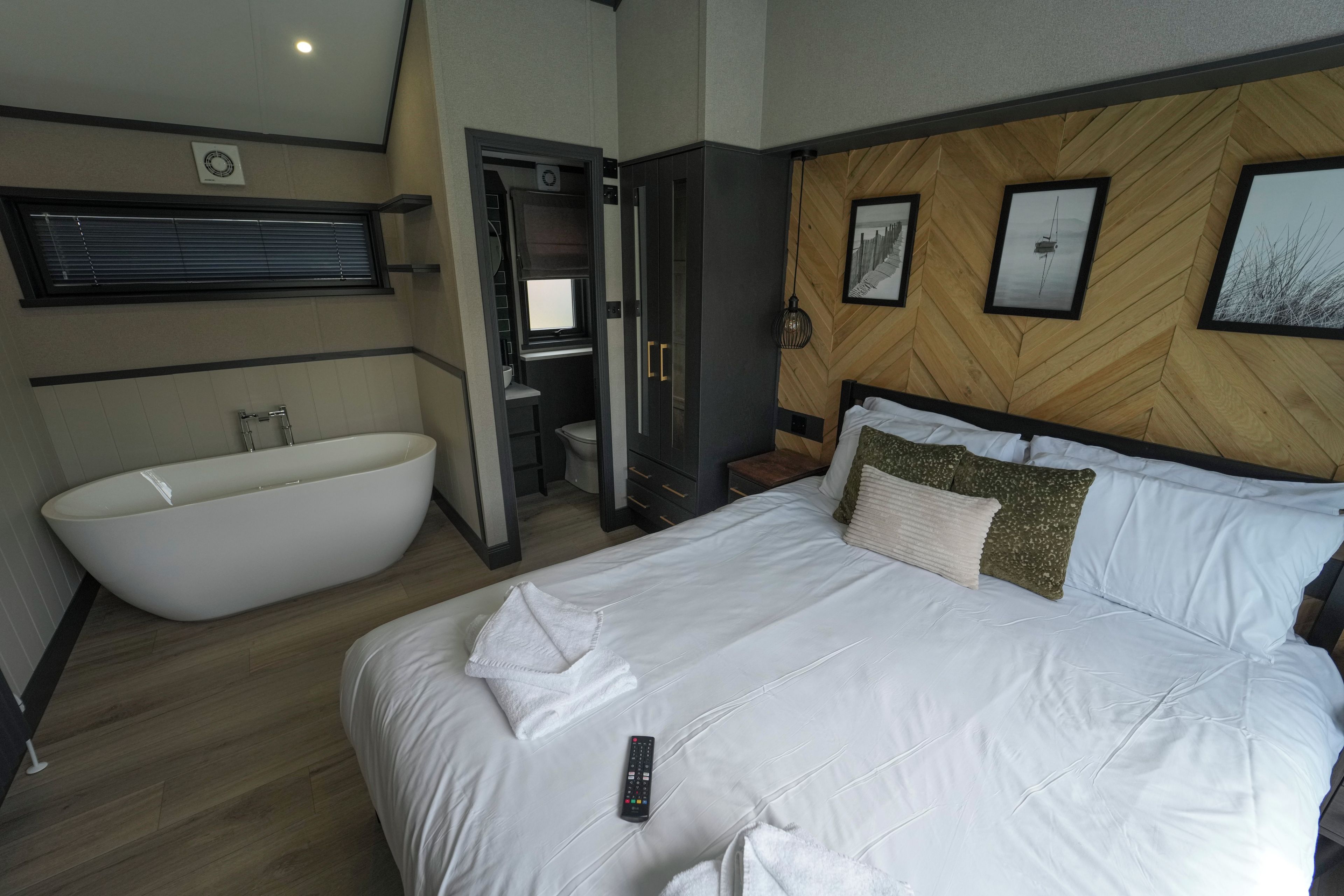 A hotel room with a large bathtub, a bed with white linens, and a wooden headboard.