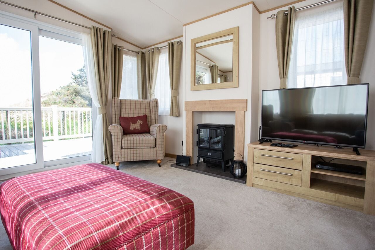 Ein Schlafzimmer mit Bett, Fernseher, Kamin, Sessel und Balkon.