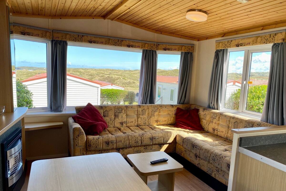 A cozy cabin interior with a sofa, a small table, and a view of the surrounding landscape.