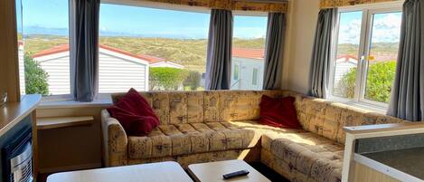 A cozy cabin interior with a sofa, a small table, and a view of the surrounding landscape.