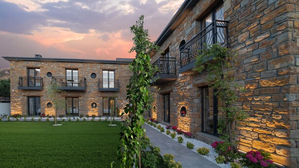 Un edificio de piedra con varios balcones y un jardín bien cuidado.