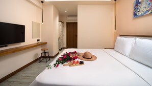 Una habitación de hotel con una cama, un televisor, un estante de madera, un escritorio y un cuadro en la pared.