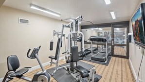 Une salle de sport équipée de matériel d’exercice, d’un tapis de course et d’une grande fenêtre offrant une belle vue.