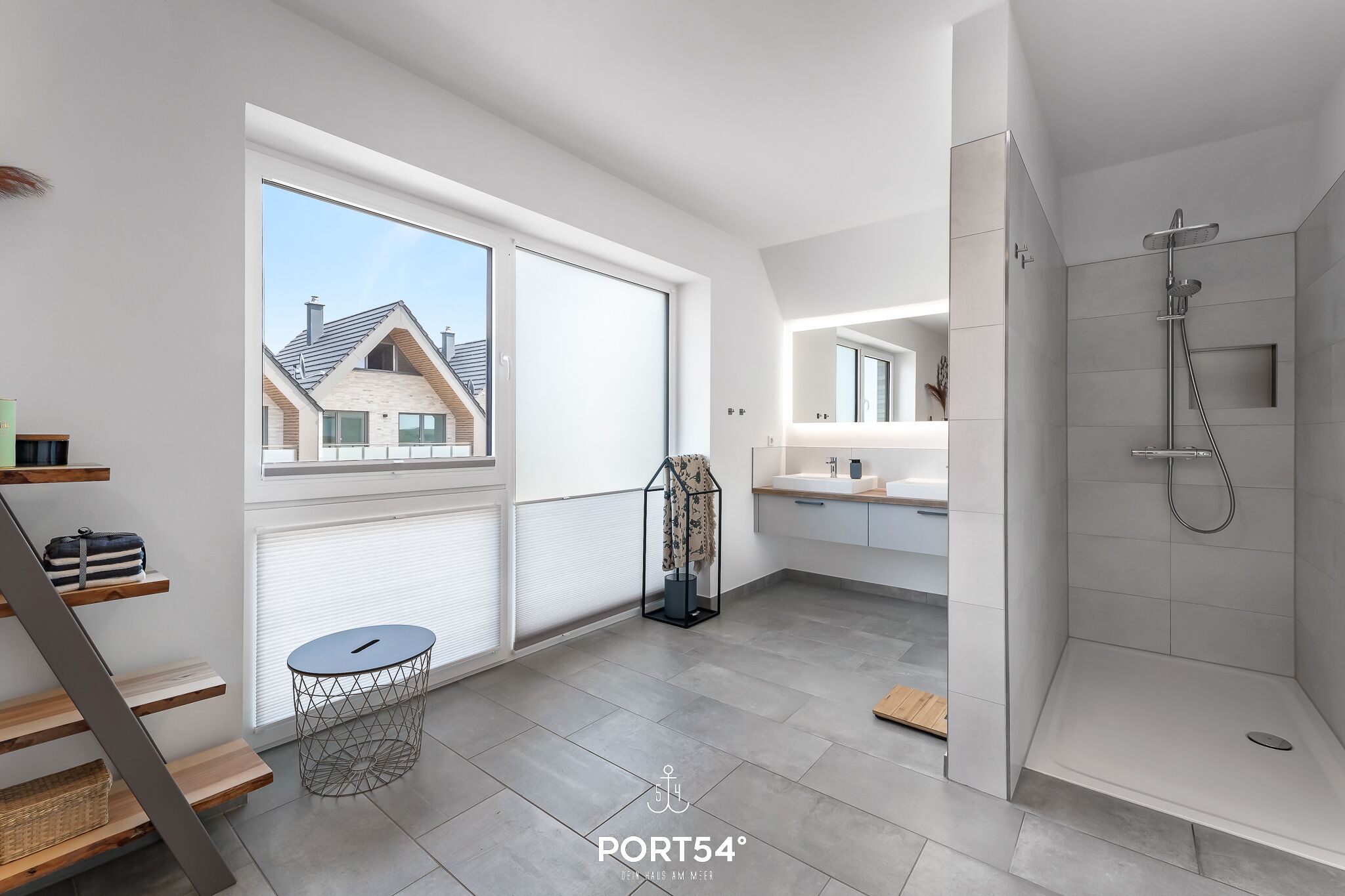 A modern bathroom with a shower, a sink, and a large window.