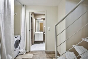 Access the bathroom through this convenient hallway featuring a washing machine and handrail.