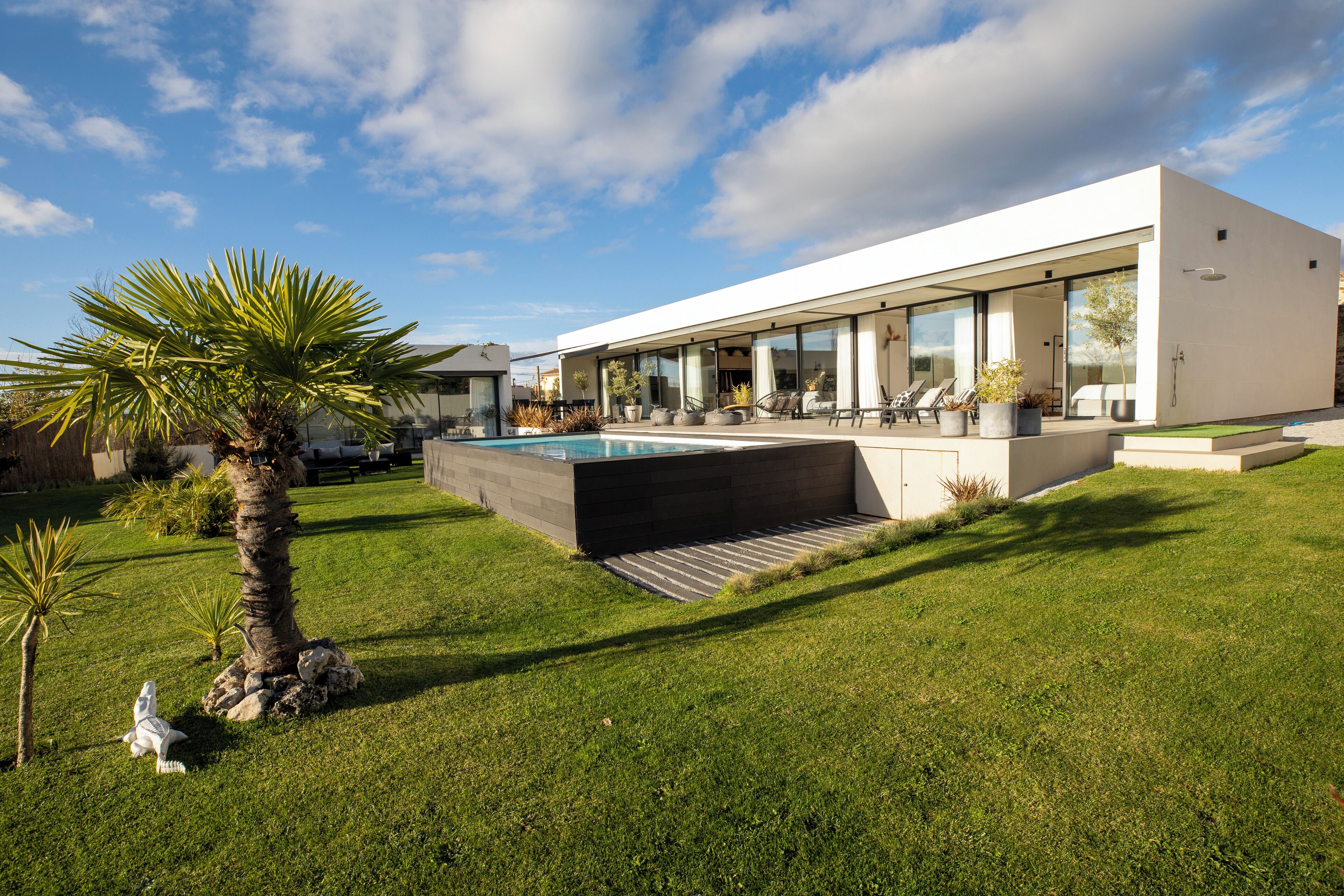 Une maison moderne dotée d’une piscine, d’un patio couvert et d’une pelouse bien entretenue.