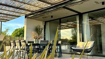 Un espace extérieur aménagé en terrasse, avec une table et des chaises, un fauteuil suspendu et une pergola.