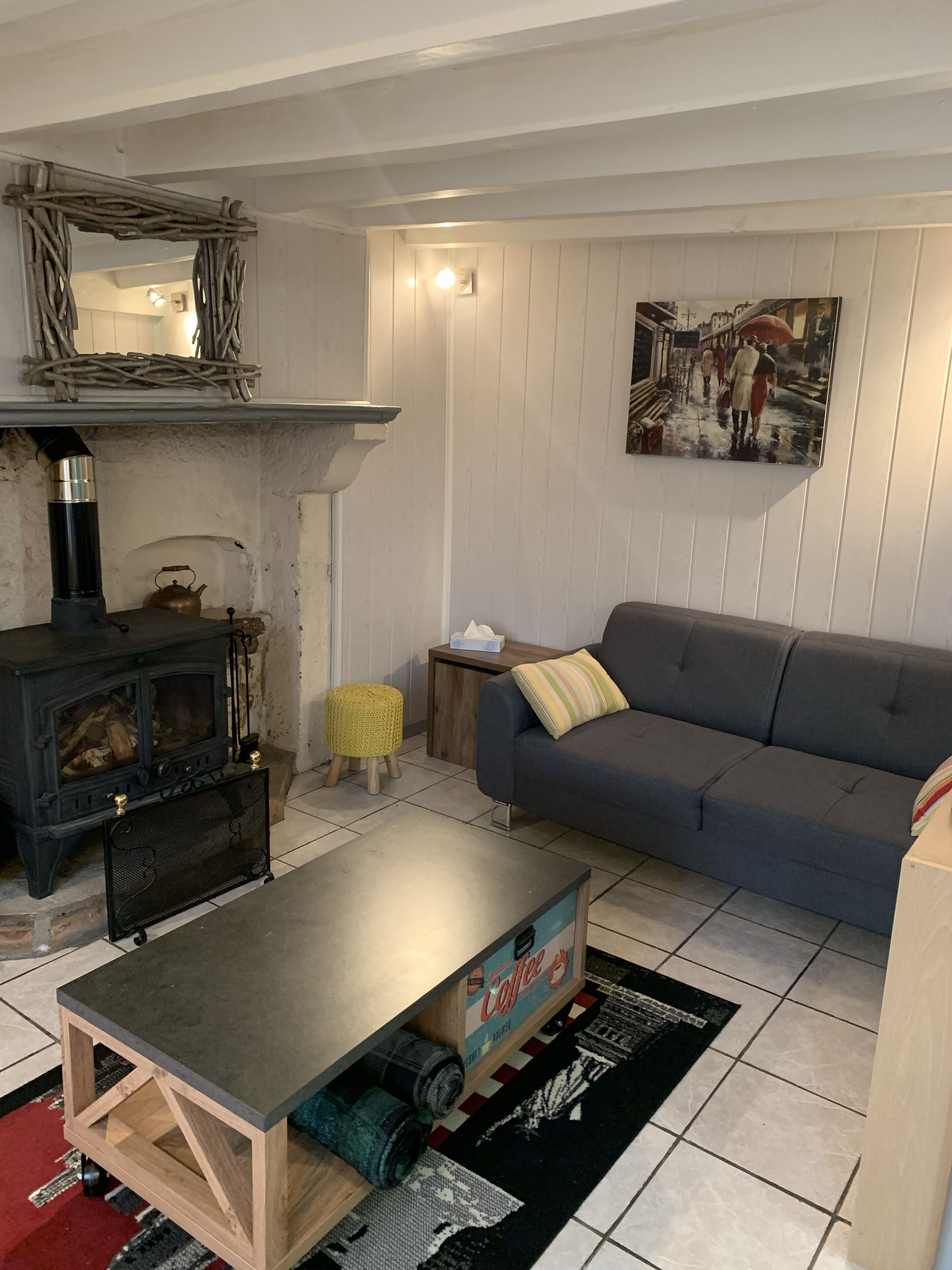 Ein gemütliches Wohnzimmer mit Kamin, Sofa, Couchtisch und einem Bild an der Wand.