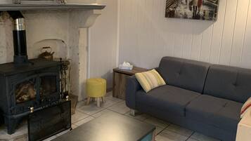 Ein gemütliches Wohnzimmer mit Kamin, Sofa, Couchtisch und einem Bild an der Wand.