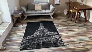 A cozy living room with a sofa, a dining table, and a patterned rug. - Our quirky Gite is 4 minutes drive to Gouzon and 12 minutes drive to Boussac. (Trois Fomds)