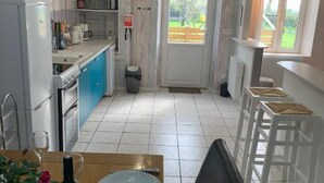 A compact kitchen with a dining area, a refrigerator, and a sink. - Our quirky Gite is 4 minutes drive to Gouzon and 12 minutes drive to Boussac. (Trois Fomds)