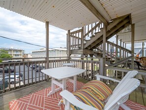 Un espace extérieur abrité doté d’une terrasse en bois, d’une table blanche et d’une chaise rembourrée.