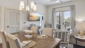 A dining area with a wooden table, chairs, a chandelier, and a ceiling fan.