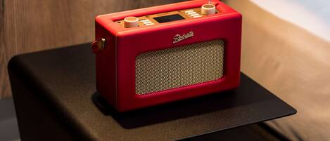 Una radio antigua roja sobre una mesa negra en una habitación de hotel.