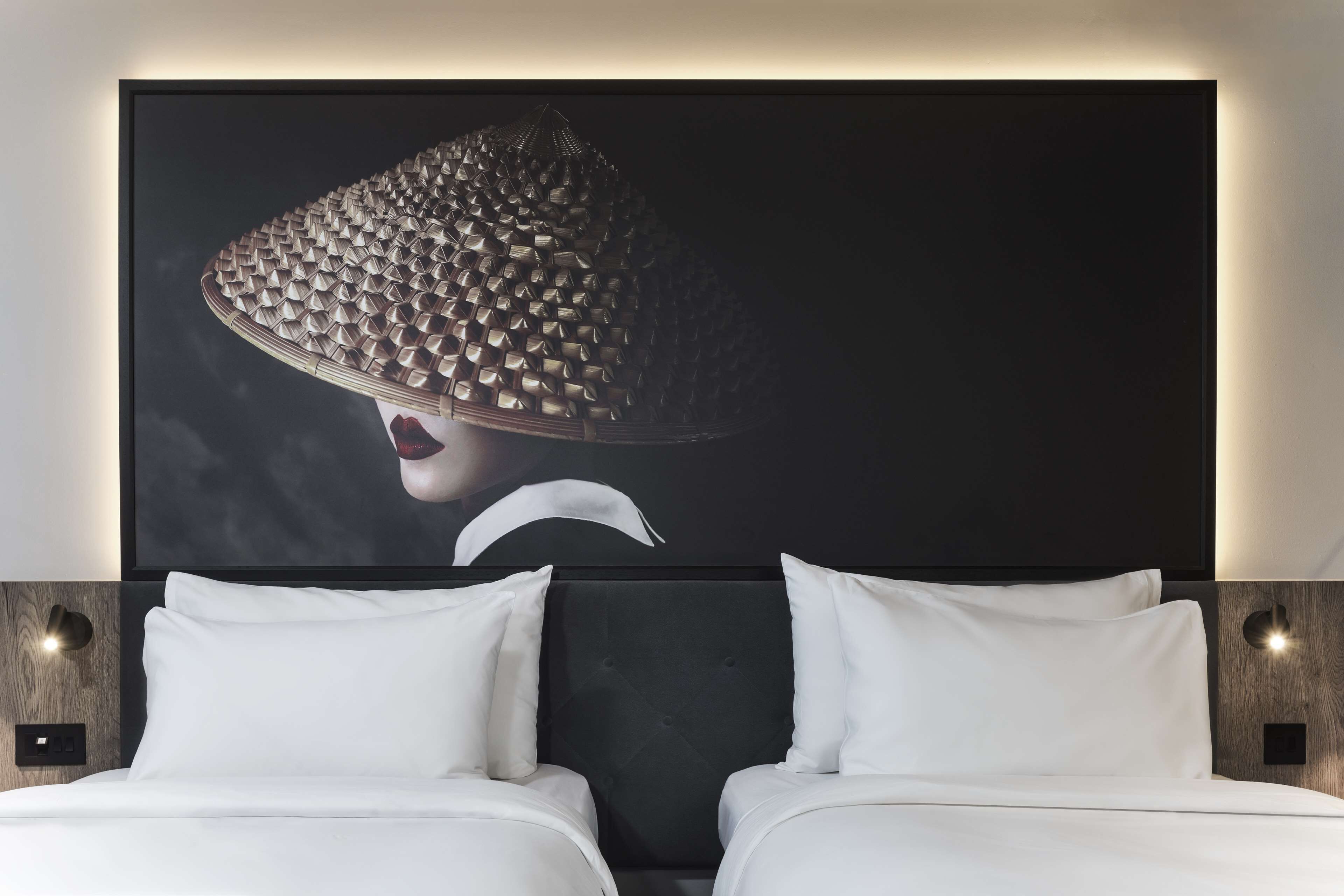 A hotel room with a large bed, two bedside tables, and a wall-mounted artwork.