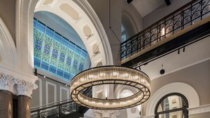 A grand lobby with a high ceiling, a chandelier, a red scooter, and a reception desk. - Radisson RED Liverpool (Liverpool)